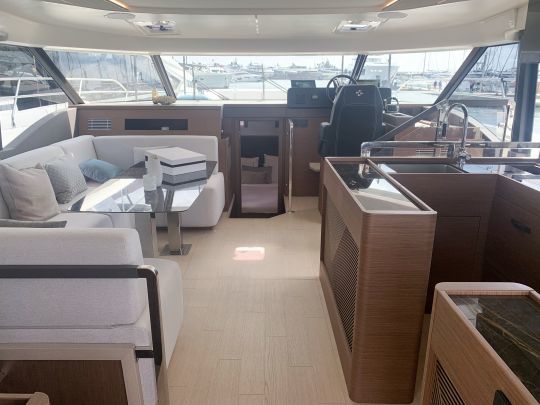 Le salon de la Prestige M48 avec un coin repas à babord, une cuisine à tribord et un poste de pilotage à tribord. Trois descentes séparées donnent accès aux trois cabines.