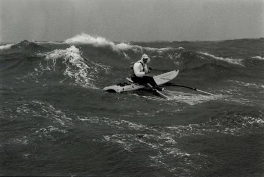 Christian Marty profite d'une pause repas sur sa planche en plein Atlantique, 1982 © Philippe Lallet 