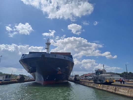Un imposant porte-conteneurs dans une &eacute;cluse du canal de Panama, guid&eacute; par les Mulas