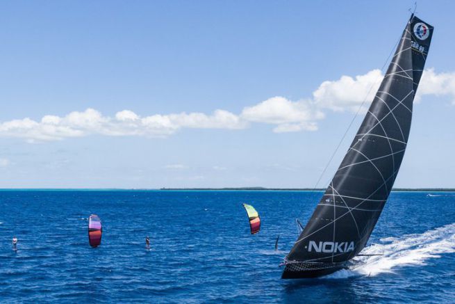 L'IMOCA Hugo Boss en course contre deux kitesurfers